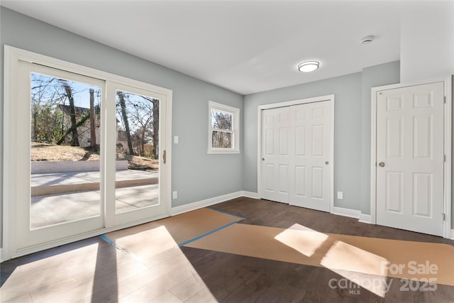 doorway featuring dark wood-style floors, baseboards, and a healthy amount of sunlight