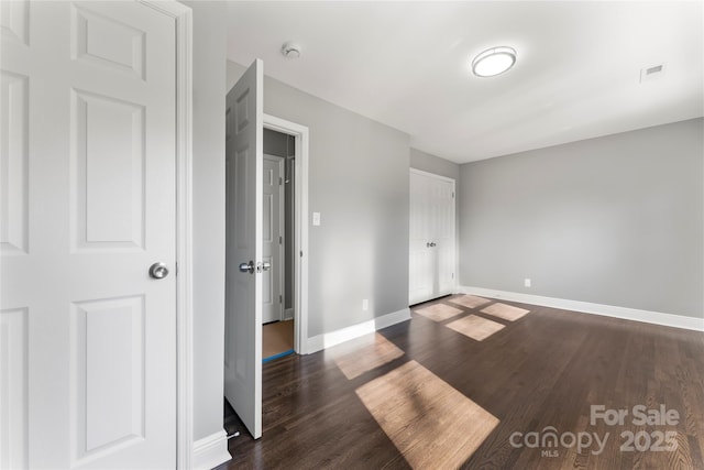 unfurnished bedroom with visible vents, baseboards, and dark wood finished floors