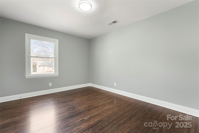 spare room with dark wood-style floors, baseboards, and visible vents