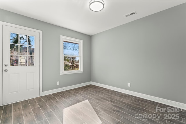 unfurnished room featuring wood finish floors, visible vents, and baseboards