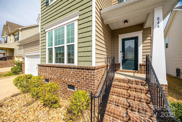 entrance to property with concrete driveway, brick siding, and a garage