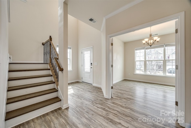 entryway featuring a notable chandelier, wood finished floors, visible vents, and a wealth of natural light