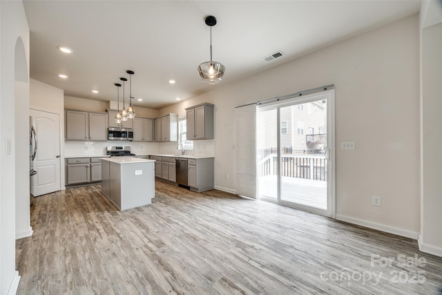 kitchen with visible vents, light wood-style flooring, gray cabinets, stainless steel appliances, and arched walkways