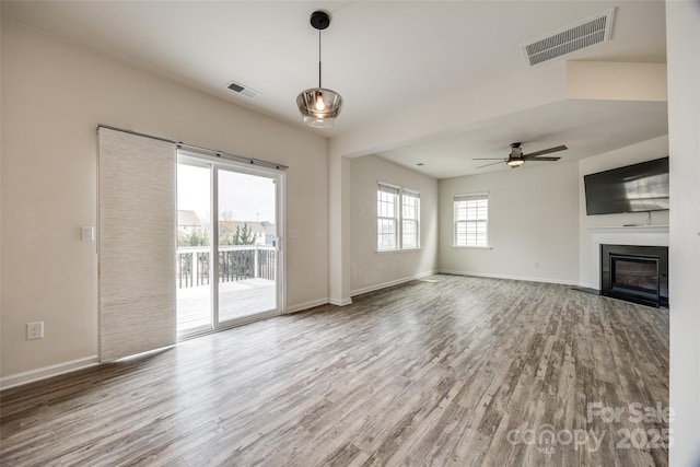 unfurnished living room with visible vents, baseboards, and wood finished floors