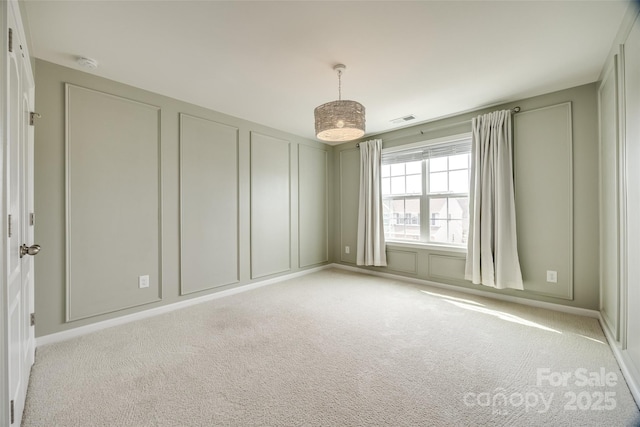 unfurnished room featuring visible vents, light carpet, and a decorative wall