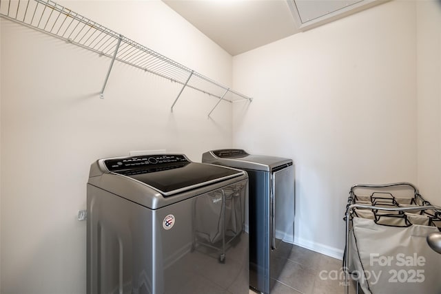 laundry room with laundry area, dark tile patterned flooring, baseboards, and washing machine and clothes dryer