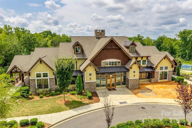 craftsman-style house featuring a standing seam roof, stone siding, french doors, roof with shingles, and metal roof