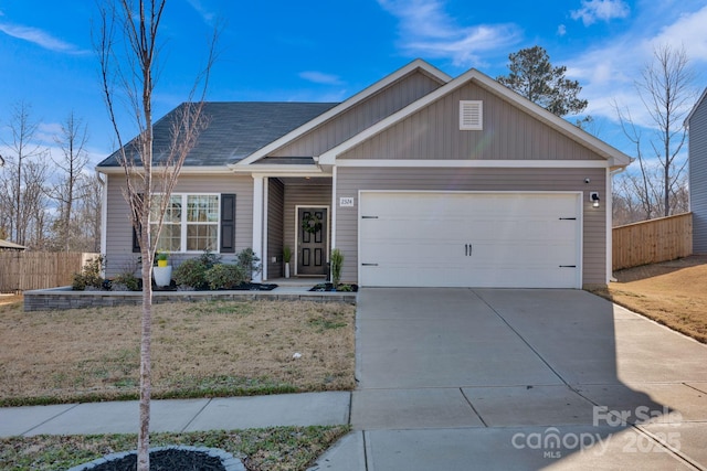 view of front of home featuring roof with shingles, concrete driveway, a front yard, fence, and a garage