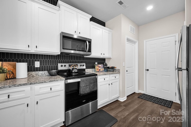 kitchen featuring stainless steel appliances, visible vents, dark wood-style floors, and white cabinetry