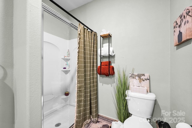 full bath with baseboards, a shower stall, and toilet