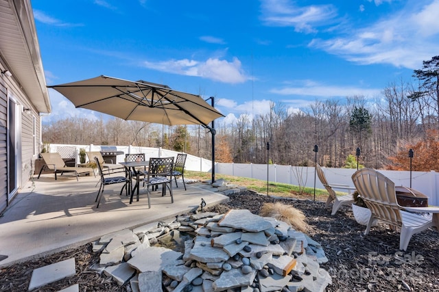 view of patio with a fenced backyard, outdoor dining area, and a view of trees