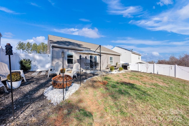 back of house featuring a fenced backyard, a fire pit, a lawn, and a patio