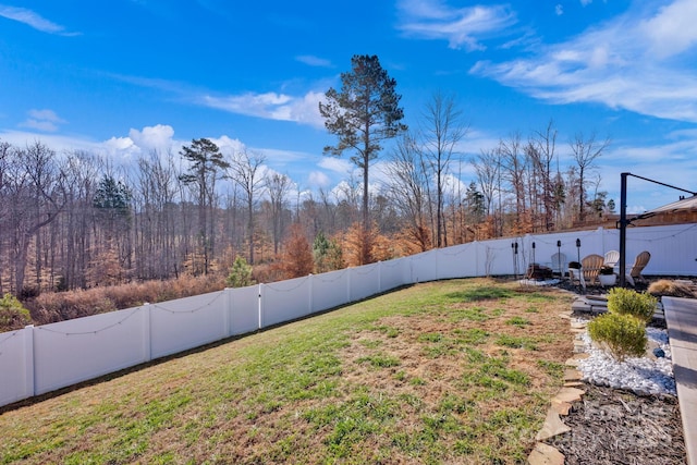 view of yard featuring a fenced backyard and a wooded view