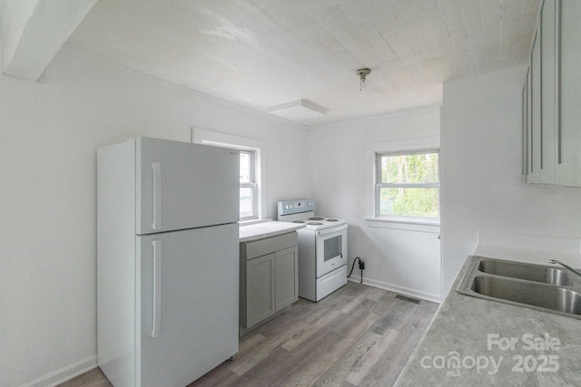 kitchen with white appliances, light wood finished floors, visible vents, light countertops, and a sink