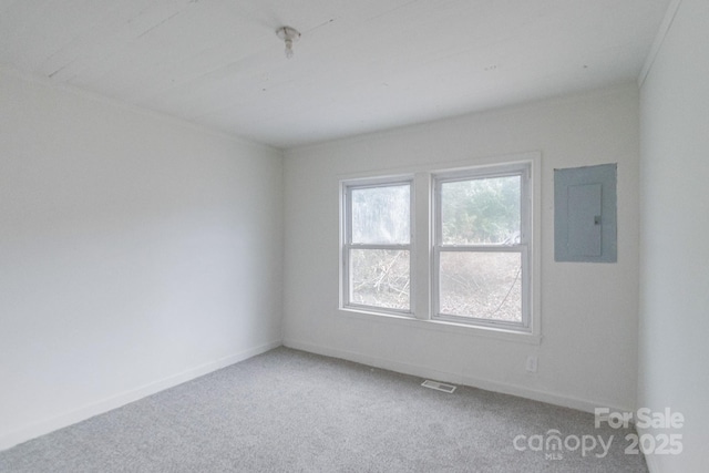 spare room with light carpet, baseboards, electric panel, and visible vents