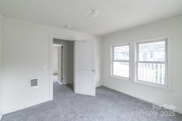 unfurnished room featuring carpet floors, visible vents, and baseboards