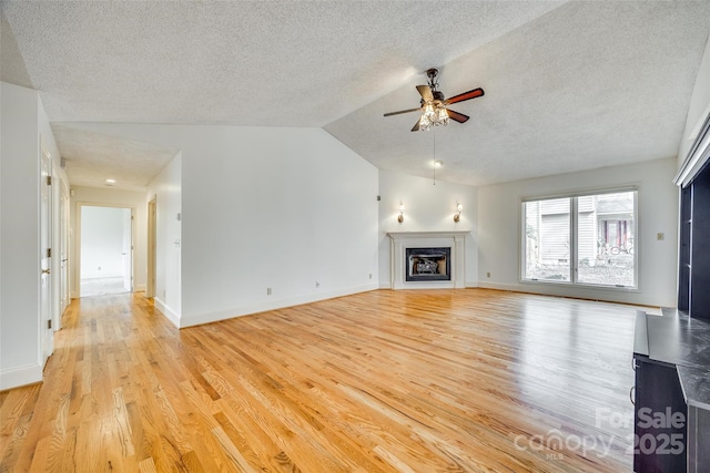 unfurnished living room featuring a ceiling fan, baseboards, lofted ceiling, light wood-style flooring, and a fireplace