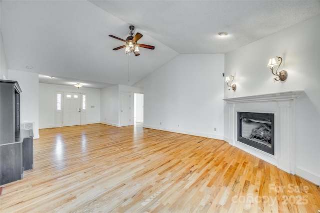 unfurnished living room with lofted ceiling, a fireplace, light wood-style floors, and ceiling fan