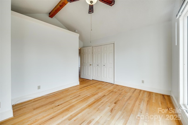 spare room with baseboards, wood finished floors, ceiling fan, and vaulted ceiling with beams