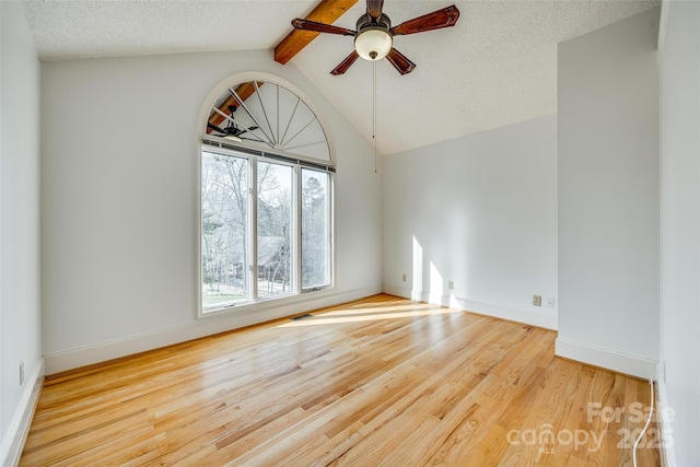 unfurnished room featuring a ceiling fan, wood finished floors, baseboards, lofted ceiling with beams, and a textured ceiling