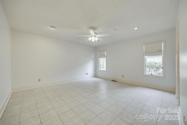 spare room featuring a wealth of natural light, baseboards, a textured ceiling, and ceiling fan