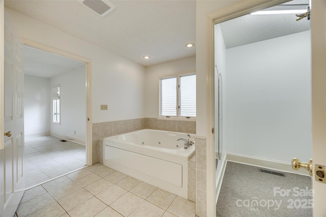 full bath featuring tile patterned floors, a tub with jets, visible vents, and a textured ceiling