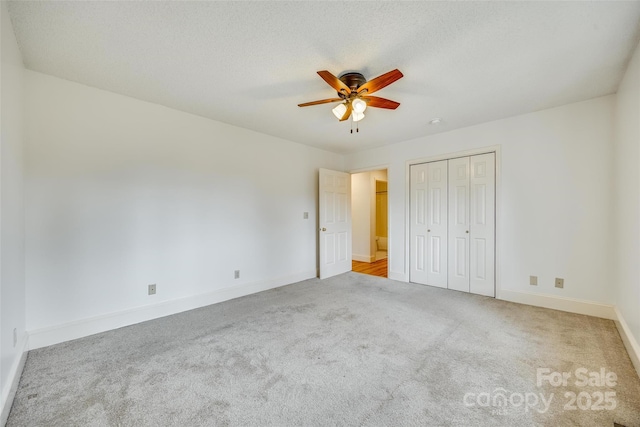 unfurnished bedroom with a ceiling fan, carpet, baseboards, a closet, and a textured ceiling