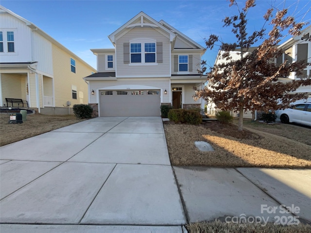 view of front of home with driveway, stone siding, and a garage