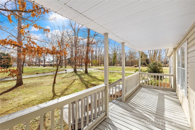 wooden deck featuring a porch and a lawn