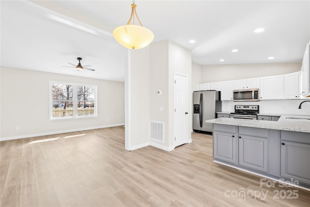 kitchen featuring a sink, visible vents, vaulted ceiling, appliances with stainless steel finishes, and light stone countertops