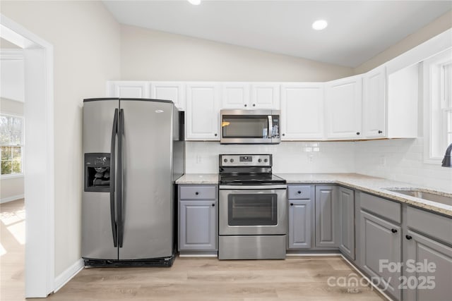 kitchen with lofted ceiling, appliances with stainless steel finishes, and gray cabinets