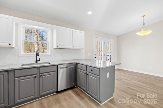 kitchen with backsplash, gray cabinetry, a sink, dishwasher, and a peninsula