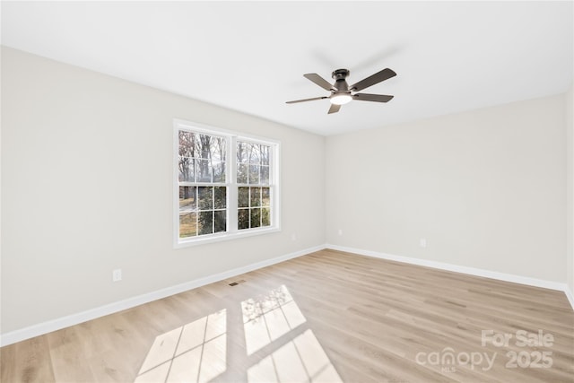 spare room featuring ceiling fan, light wood finished floors, and baseboards