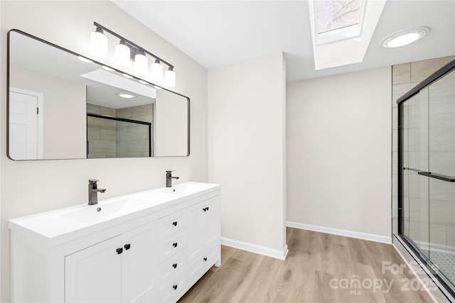 full bathroom featuring a stall shower, baseboards, a sink, and wood finished floors