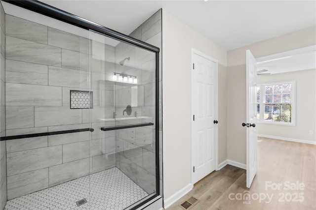 full bathroom featuring a stall shower, wood finished floors, visible vents, and baseboards