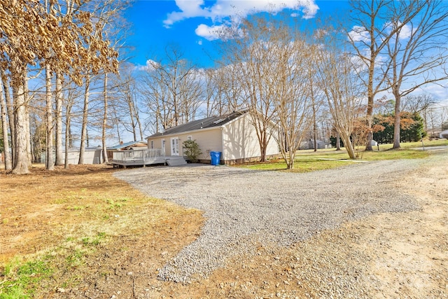 view of side of property featuring a deck and gravel driveway