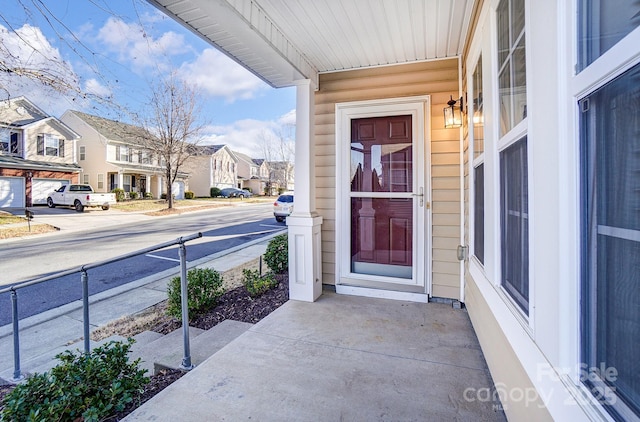 doorway to property featuring covered porch and a residential view