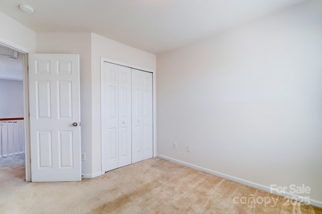 unfurnished bedroom with a closet, baseboards, and carpet flooring