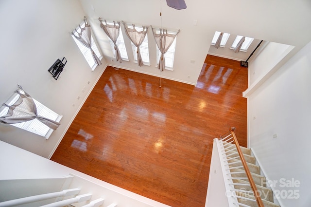 interior space with ceiling fan, stairway, baseboards, and wood finished floors