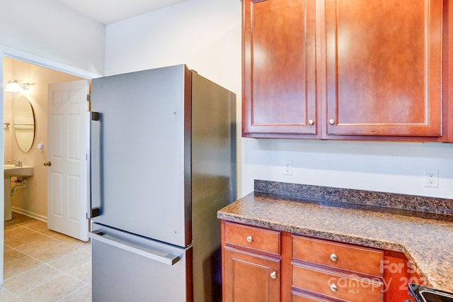 kitchen featuring light tile patterned floors, dark countertops, stove, freestanding refrigerator, and built in study area