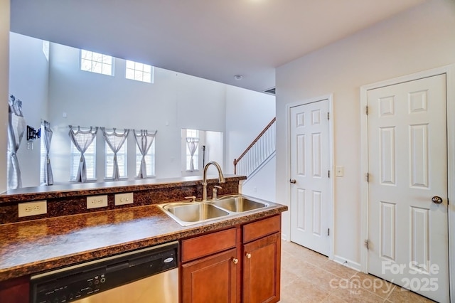 kitchen featuring light tile patterned floors, a sink, brown cabinets, dishwasher, and dark countertops