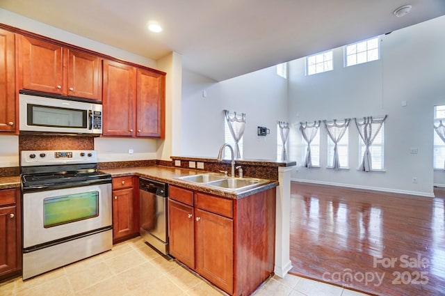 kitchen with a peninsula, plenty of natural light, appliances with stainless steel finishes, and a sink