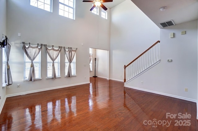 unfurnished living room featuring hardwood / wood-style flooring, baseboards, and a ceiling fan