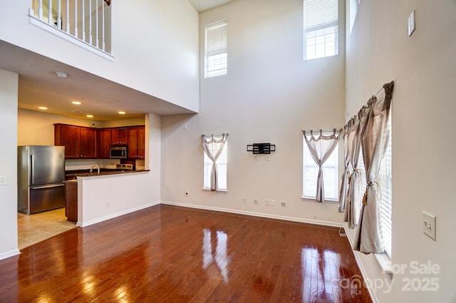 unfurnished living room with baseboards, wood finished floors, and recessed lighting