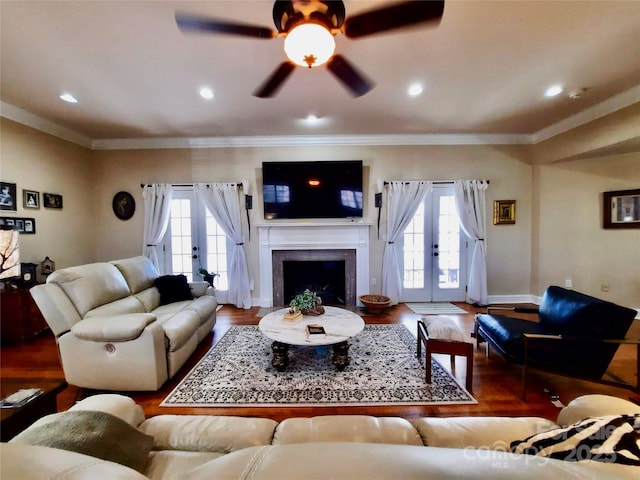 living area featuring french doors, a fireplace, crown molding, and wood finished floors