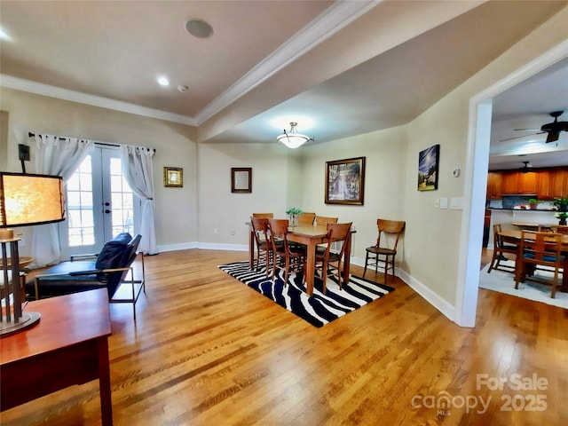 dining area with baseboards, ceiling fan, wood finished floors, crown molding, and french doors