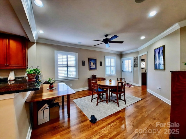 dining room with light wood-style floors, recessed lighting, crown molding, and baseboards