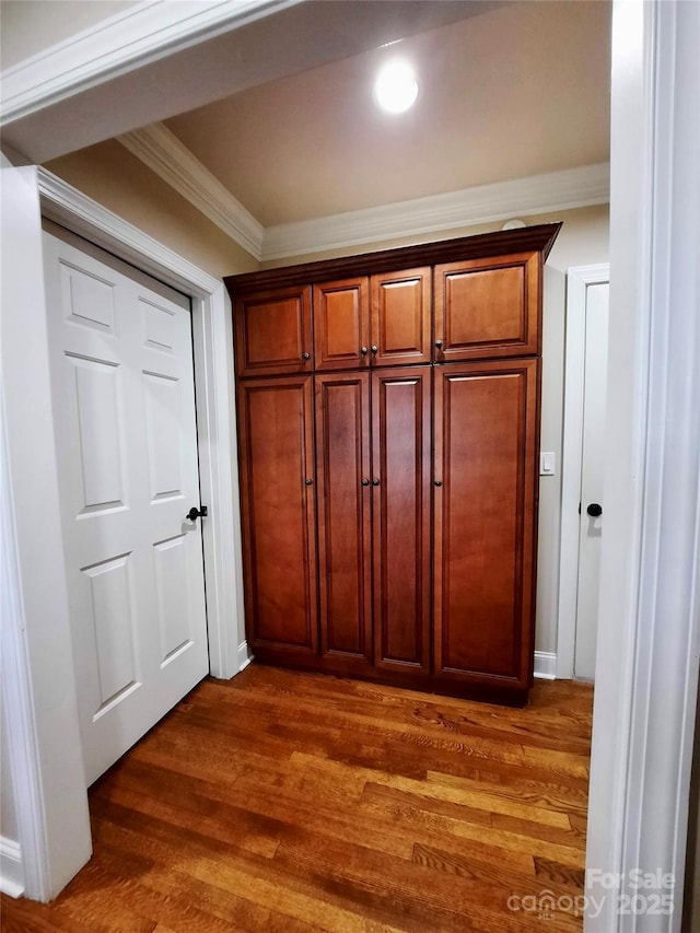 hallway featuring dark wood-style floors, baseboards, arched walkways, and crown molding