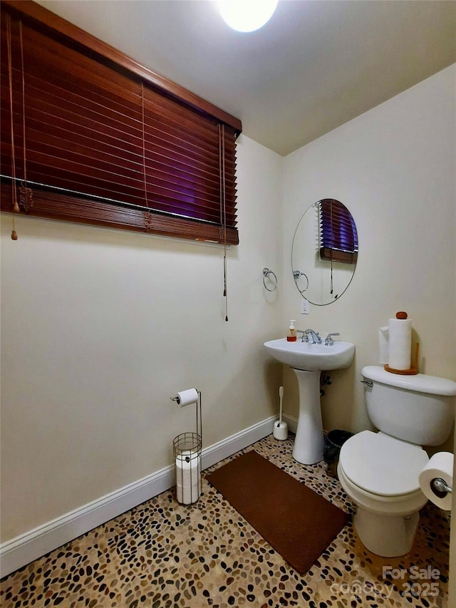 bathroom with baseboards, a sink, and toilet