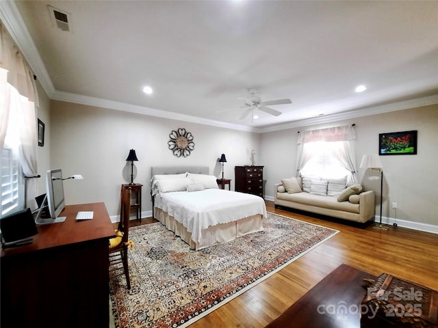 bedroom with visible vents, crown molding, baseboards, and wood finished floors